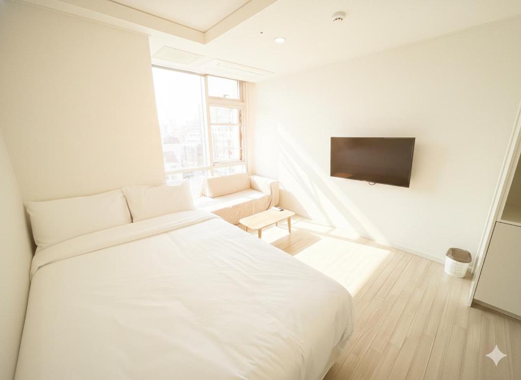 a white bedroom with a bed and a couch at The Hide City in Jeju