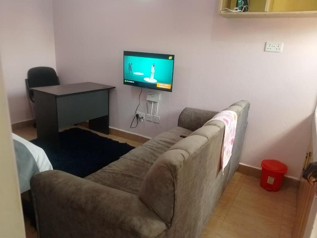 a living room with a couch and a tv on a wall at Masqani studios muthiga in Rungiri