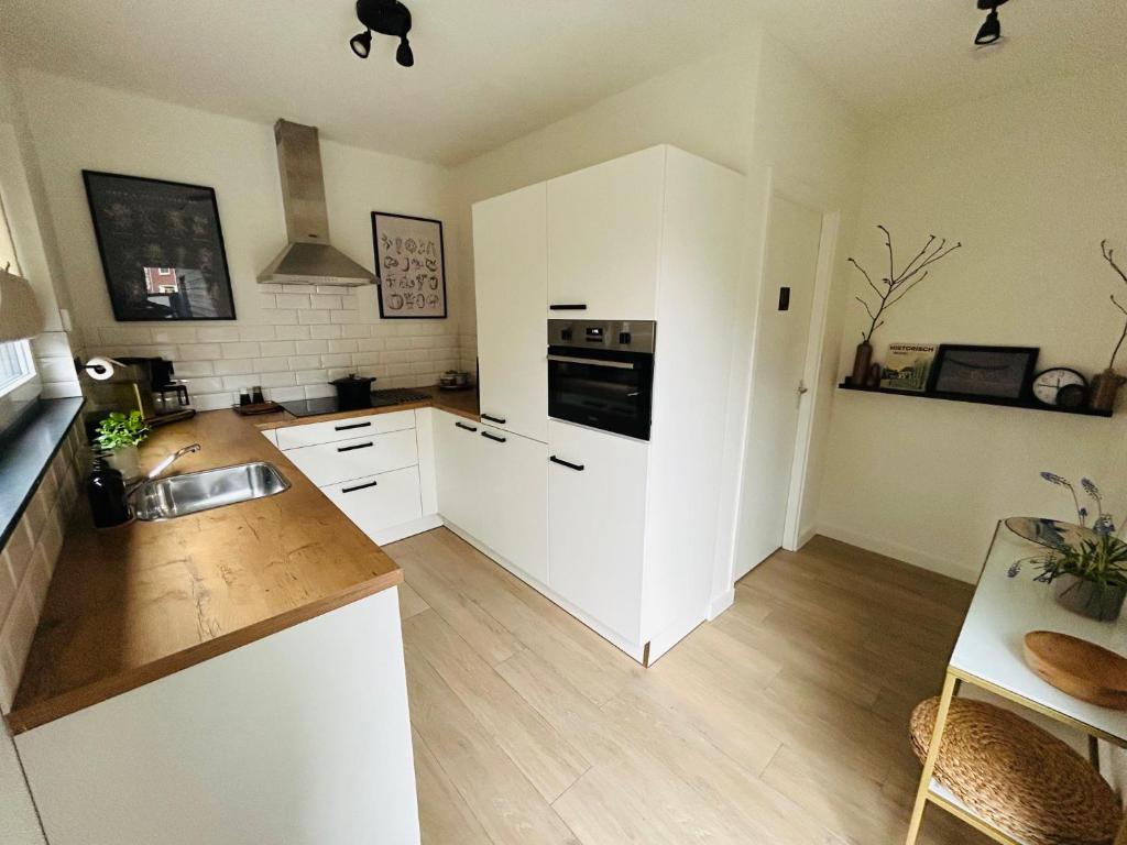 a kitchen with white cabinets and a stove top oven at Ons huisje in Schoot in Budel-Schoot