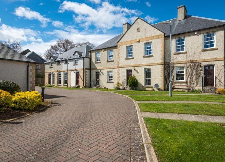ein großes Haus mit einer gepflasterten Auffahrt davor in der Unterkunft Abbey Mill in Melrose