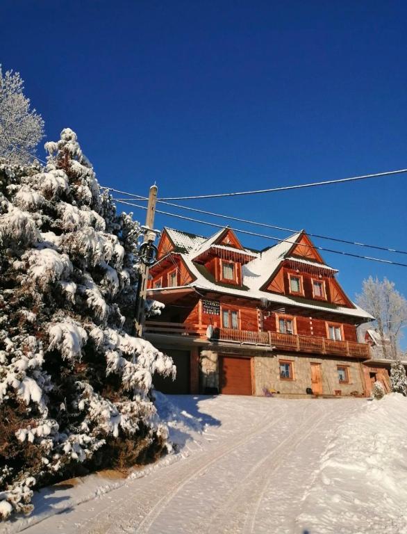 a large wooden house with snow on it at Miodowa Chatka in Brzegi