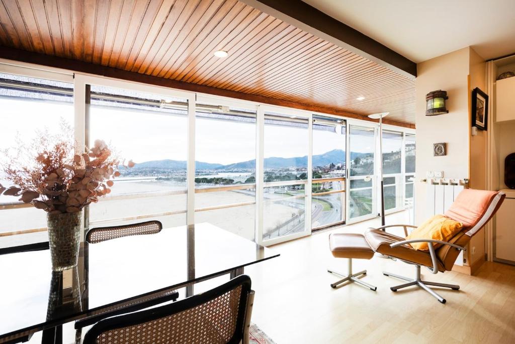 a room with a table and chairs and large windows at Itsas aurre Basquenjoy in Fuenterrabía