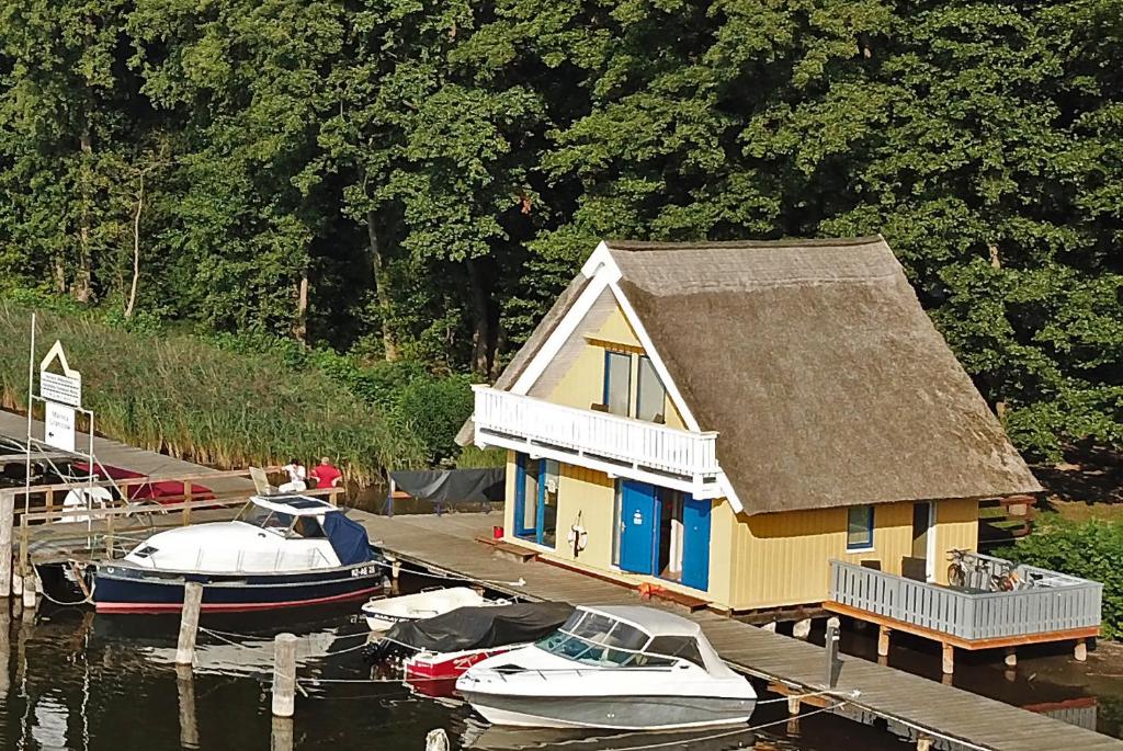 a house on a dock with boats docked in the water at Bootshaus 600 in Mirow