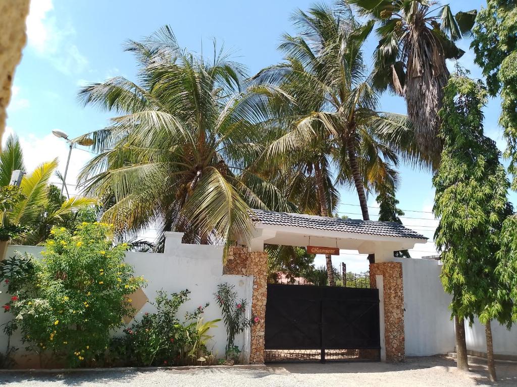 a villa with palm trees behind a white fence at Kamsons in Mombasa