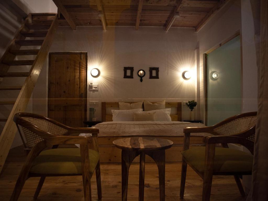 a bedroom with a bed and two chairs and a table at Kuhama Private Mountain Chalet Naggar in Nagar