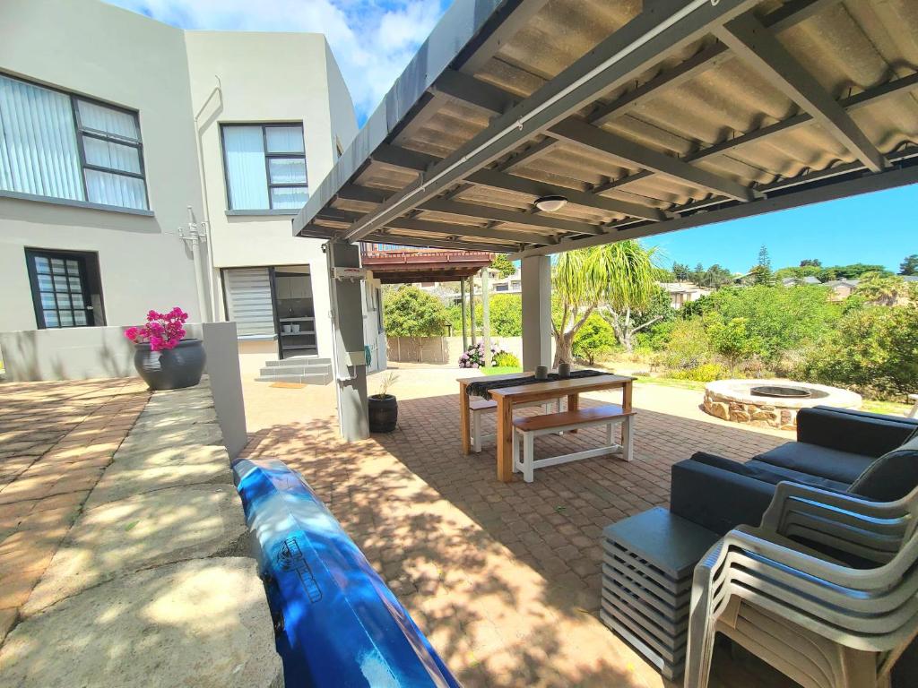 a patio with a wooden pergola and a table at VitaminSea in Mossel Bay