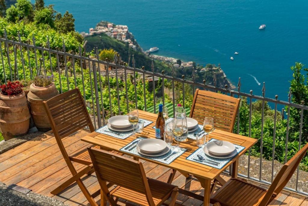 a wooden table and chairs on a deck with a view of the ocean at Orizzonte Damare in Volastra
