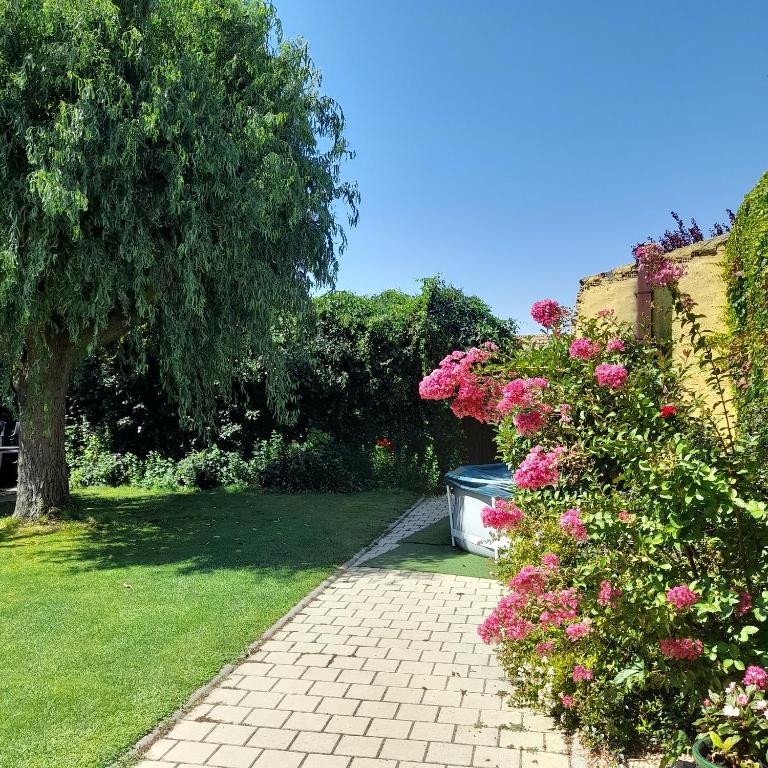 a garden with pink flowers and a brick walkway at El Molino in Nieva