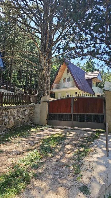 a fence in front of a house with a tree at Vikendica Rujiste in Mostar