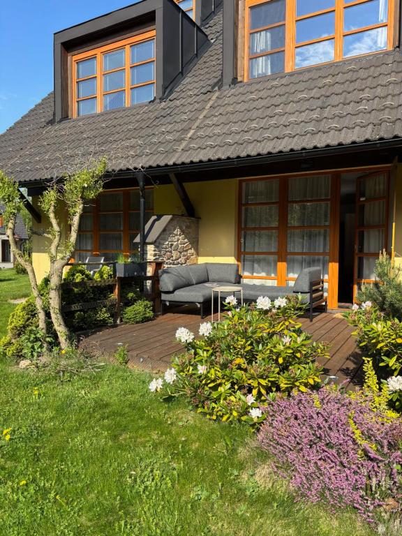 a house with a patio with a couch and flowers at Apartmán Vratička Říčky v Orlických horách in Říčky