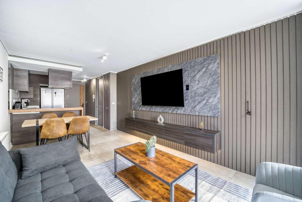 a living room with a couch and a tv on a wall at Eluchans One with Pool & parking near Reñaca Beach in Viña del Mar