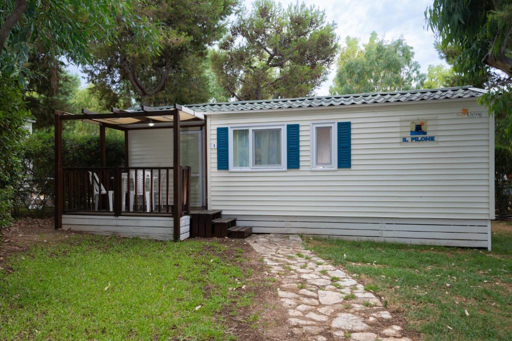 a small white house with a porch and a deck at Camping Villaggio Il Pilone in Rosa Marina