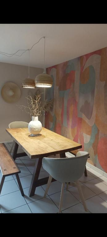 a dining room table with a vase on top of it at Gîte Minimalist indépendant au calme in Commentry
