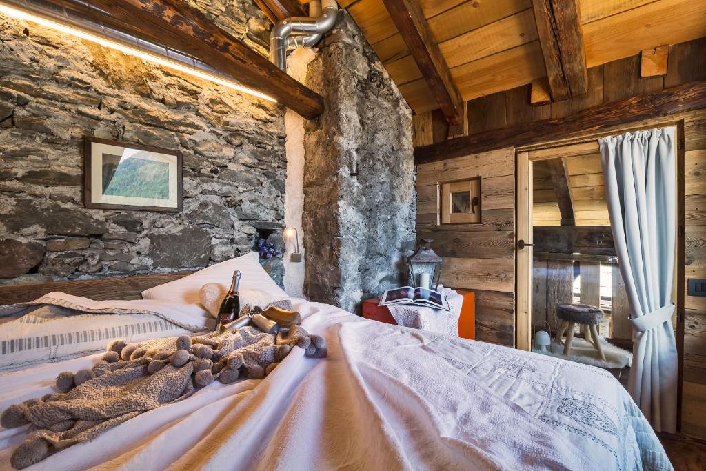 1 dormitorio con 1 cama en una pared de piedra en Maison La Saxe, en Courmayeur