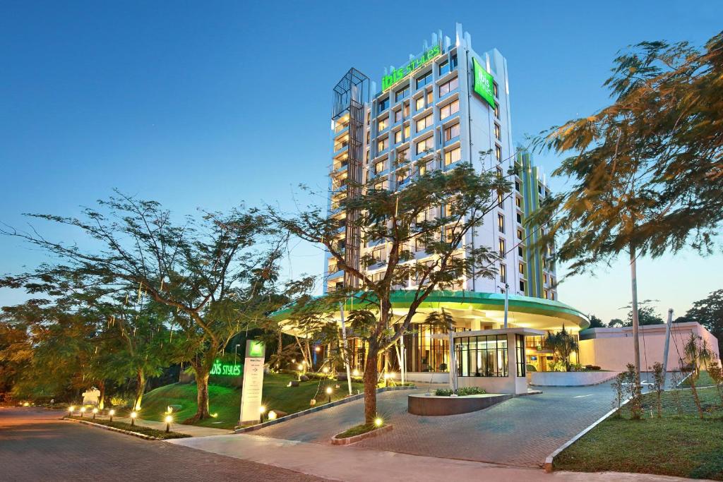 a hotel with a building with trees in front of it at Ibis Styles Bogor Raya in Bogor