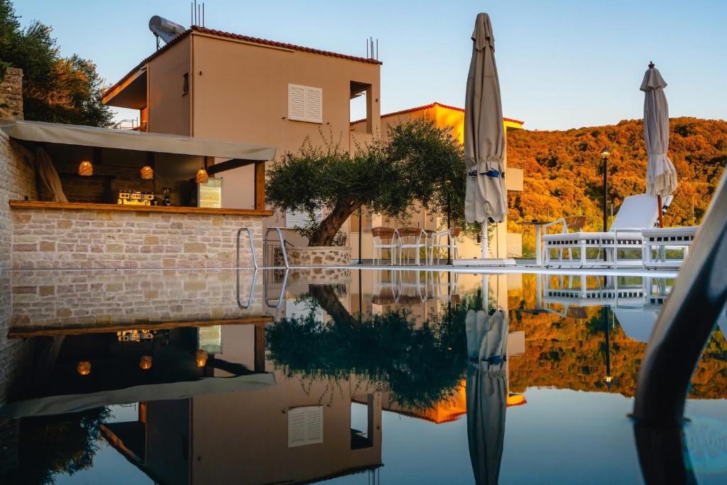 a villa with a swimming pool and an umbrella at Rizos Bay Sarakiniko in Sarakiniko