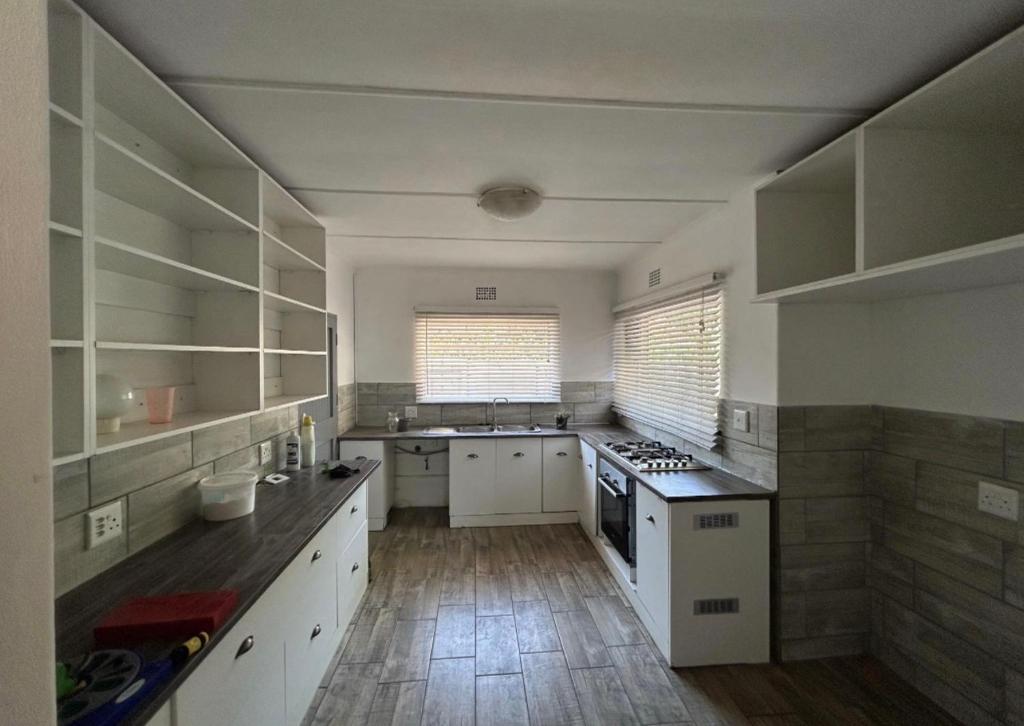 eine große Küche mit weißen Schränken und Holzboden in der Unterkunft Madlabeezy in Kempton Park