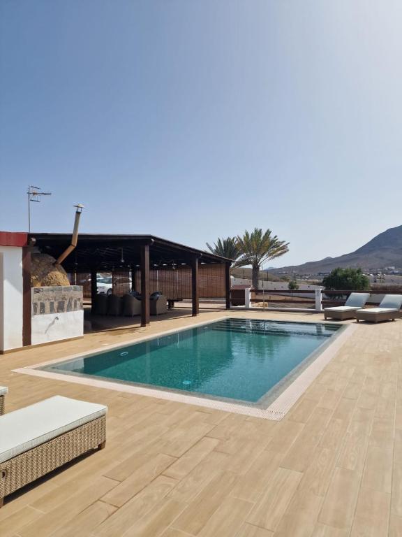 a swimming pool with a wooden floor and a building at Casa Abuela Serapia in Tuineje