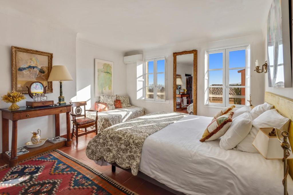 a bedroom with a bed and a desk and windows at La Maison du Prince in Grimaud