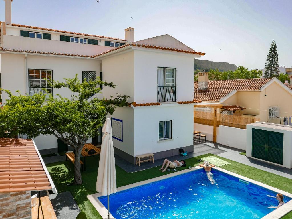 a villa with a swimming pool in front of a house at SURFinn Lisbon in Costa da Caparica