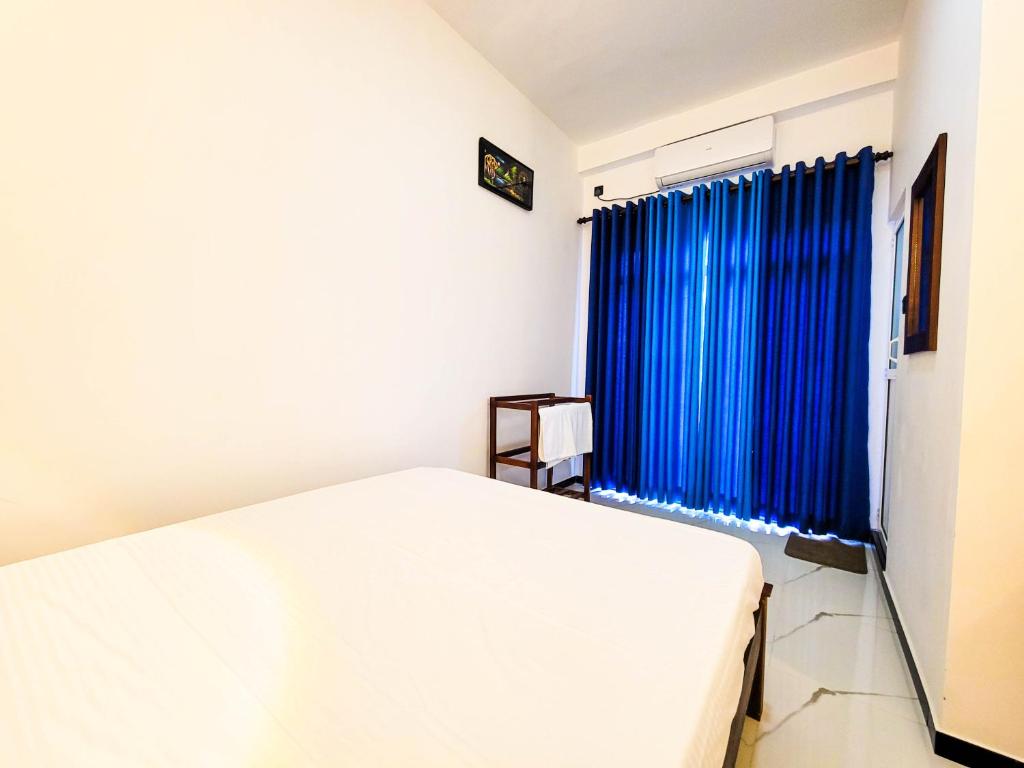 a white bed in a room with a blue curtain at Cloud View Family Villa in Kandy