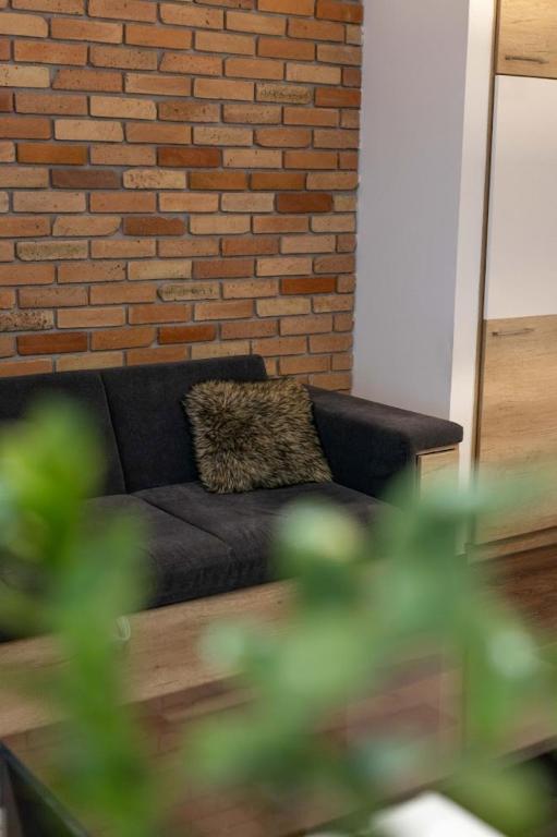 a black couch in a living room with a brick wall at City Royal Studio in Székesfehérvár