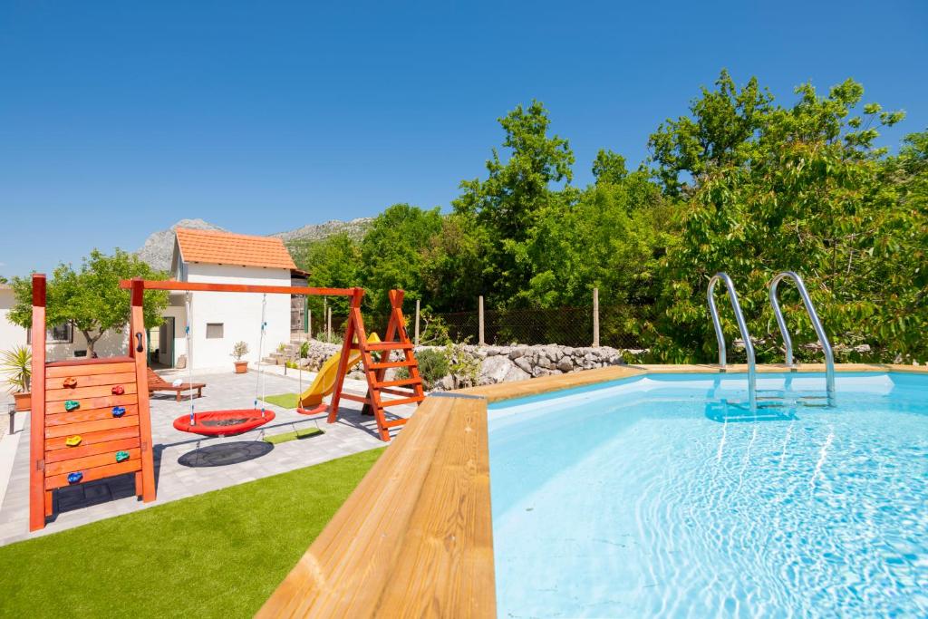 a backyard with a pool with a slide and a playground at Nika Vacation House in Zavojane