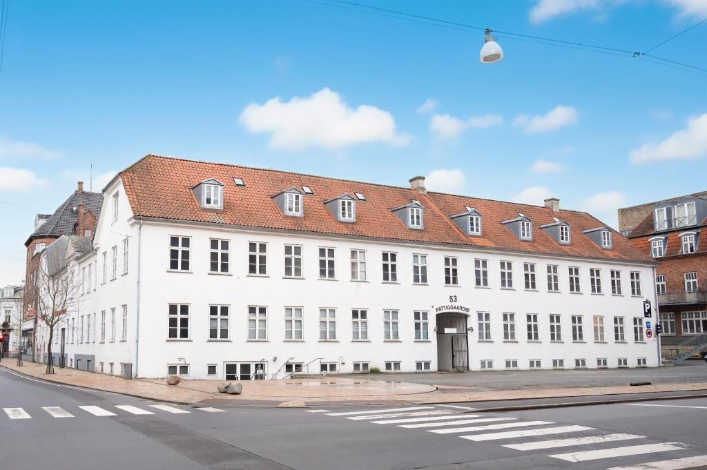 a large white building with a red roof on a street at Princessen på ærten in Odense