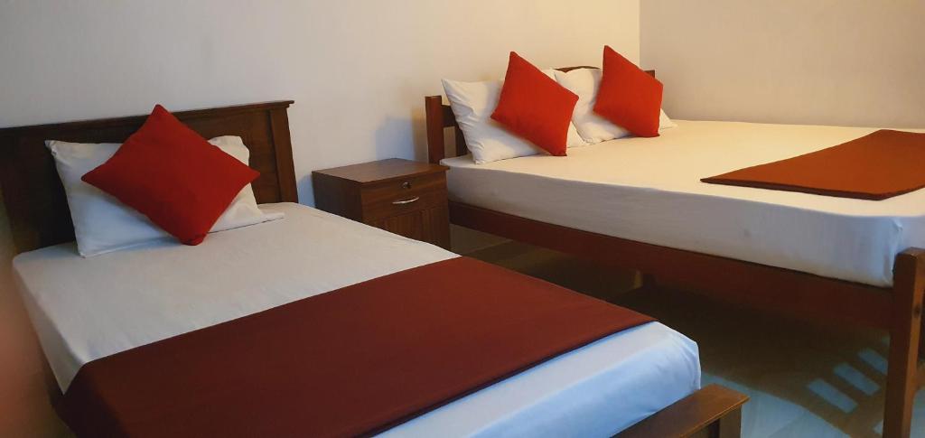 two beds with red pillows in a room at Dee Ella hotel in Danowita