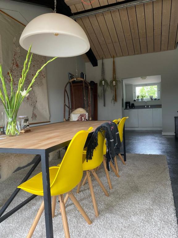 a dining room with a table and yellow chairs at Slapen bij Uppruna in Chaam