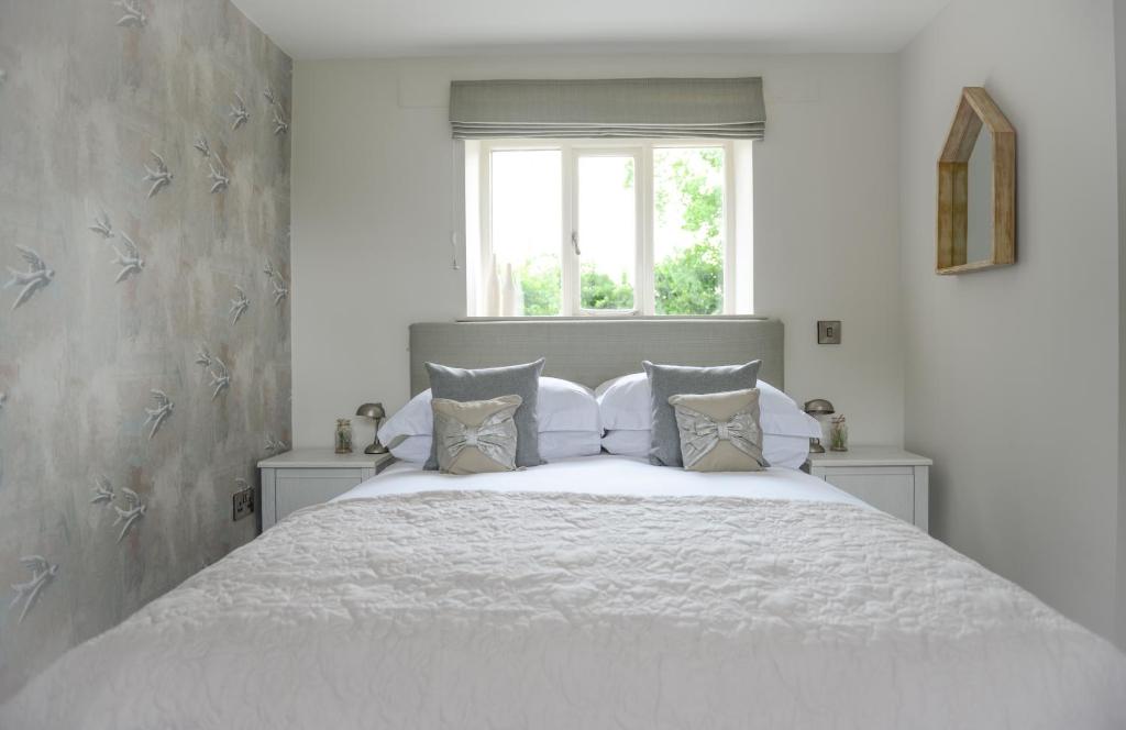 a bedroom with a white bed with a window at Cromhall Farm in Chippenham