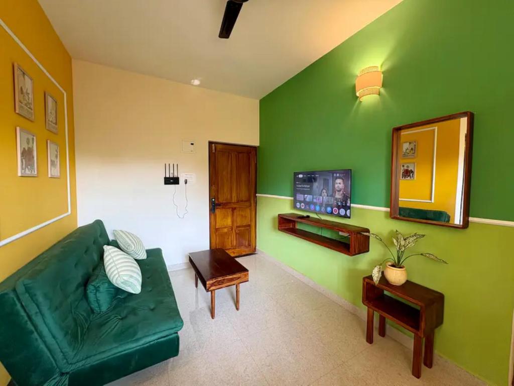 a living room with a green couch and a television at The Habitat By Locomo in Mandrem