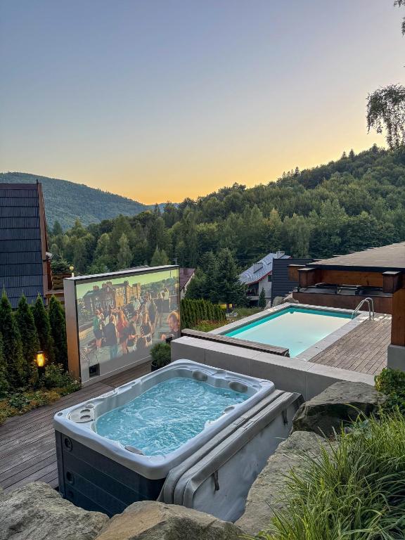 a hot tub sitting on a deck next to a swimming pool at Niebo Beskidu in Brenna