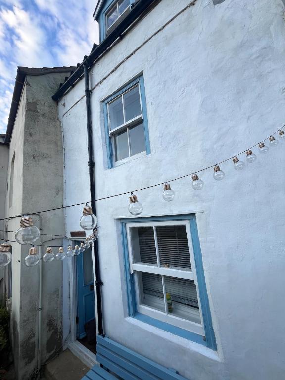 a white building with a blue window and a string of lights at Foretop Cottage, Staithes in Staithes