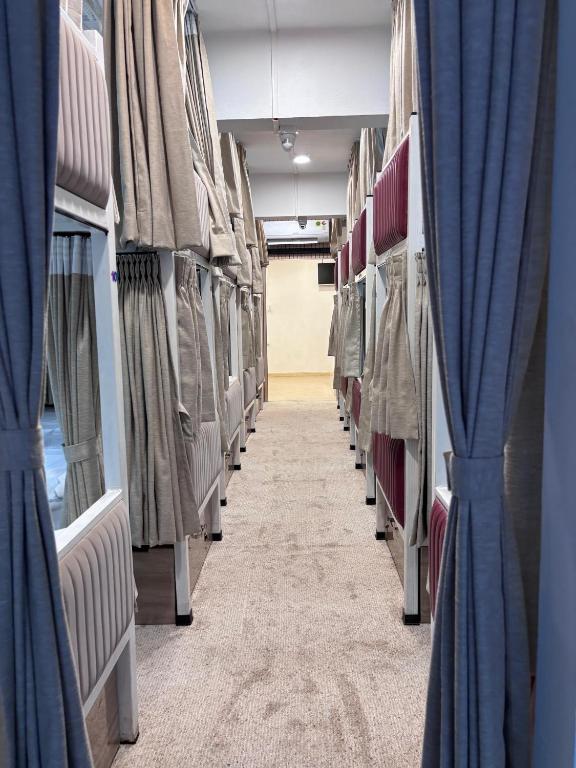 an aisle in an empty train with blue curtains at Rajal Dormitory in Indore