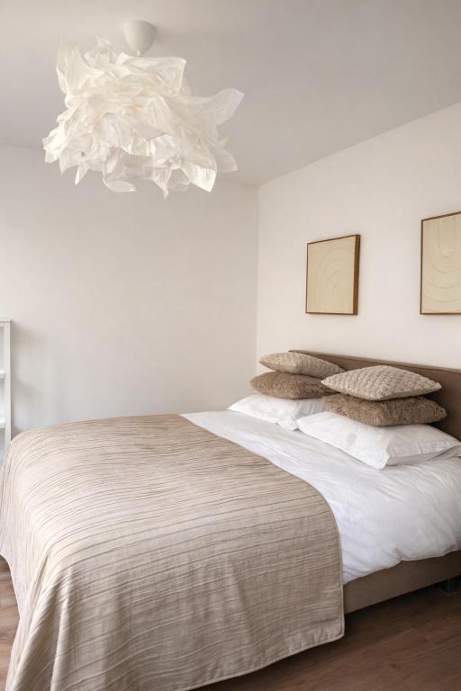 a white bedroom with a large bed and a chandelier at Boutique appartementen Théodore in Valkenburg