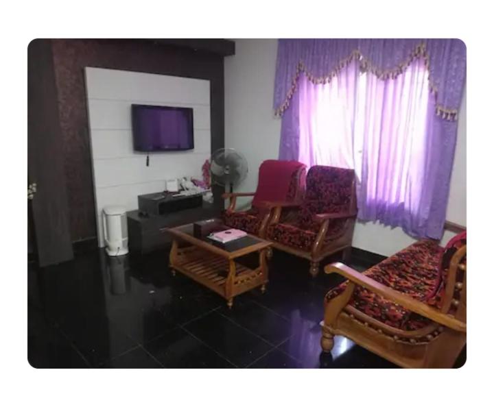 a living room with two chairs and a tv at Dream Home in Irimbranallūr