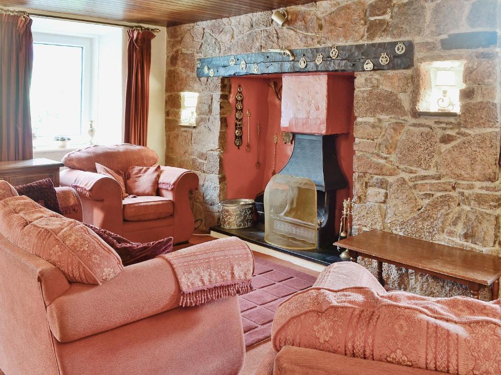 a living room with a stone fireplace with two couches at Hen Ysgol in Llanfaethlu