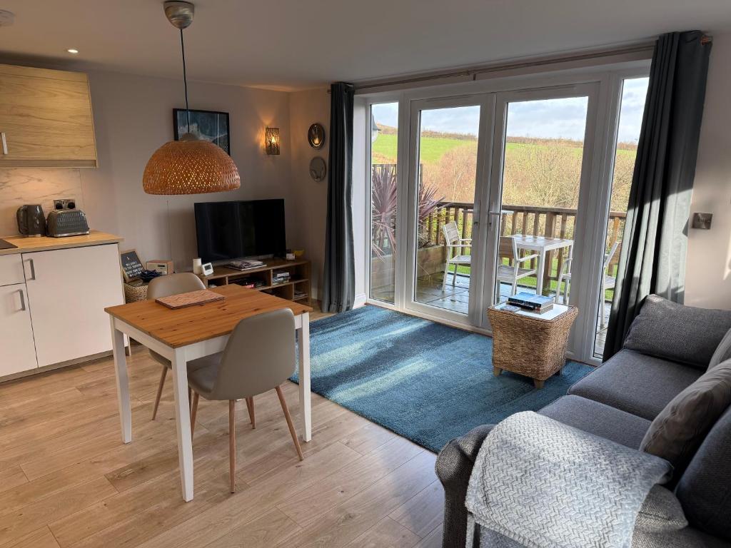 a kitchen and a living room with a table and a couch at The Burrow Devon in Longdown