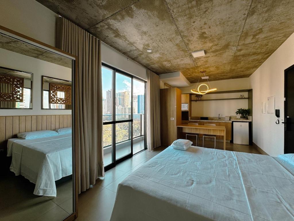 a bedroom with two beds and a large window at Apto Moderno no Coração da Cidade - CA802 in Maringá