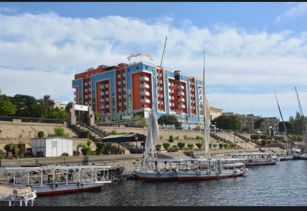 a large red and blue building with boats in the water at Nile Plaza Guest House in Aswān