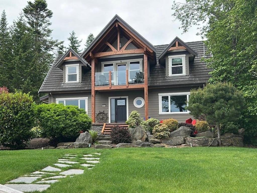 a house with a green lawn in front of it at Large ocean view family retreat in Comox
