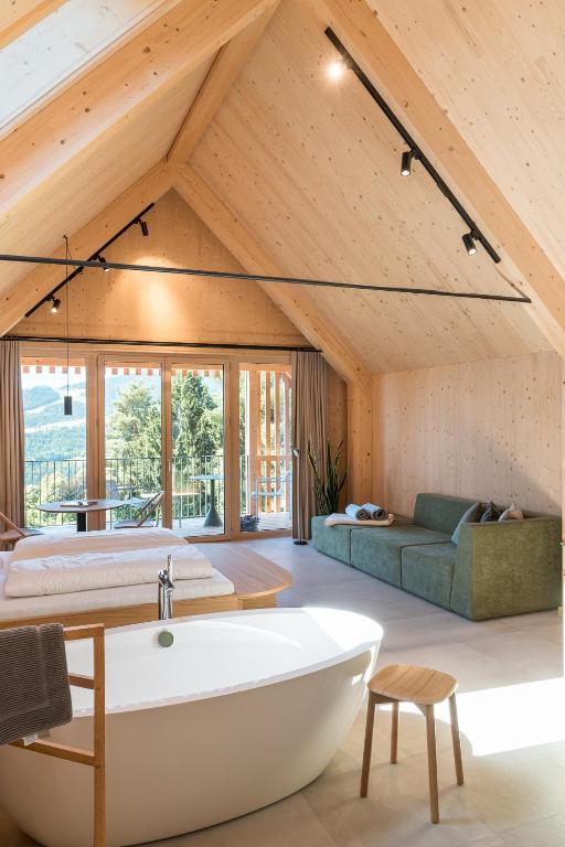 a large bathroom with a tub and a bed and a couch at SCHILCHERLANDLEBEN - Hochgrail in Greisdorf