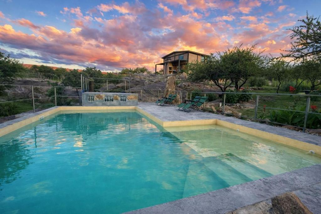 a large swimming pool with a house in the background at Kuntur Casas de Campo in Mina Clavero