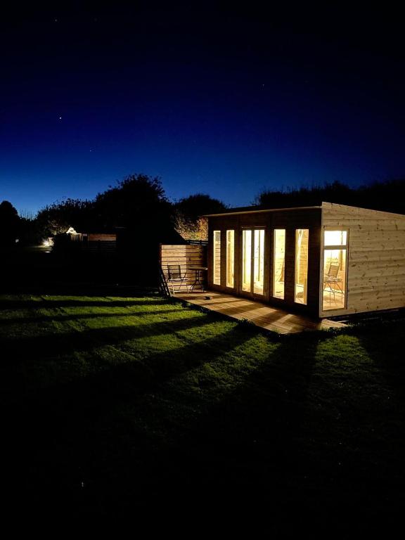 a small building with windows in a yard at night at Yellowhammer Hut at Carr House Farm in Cayton