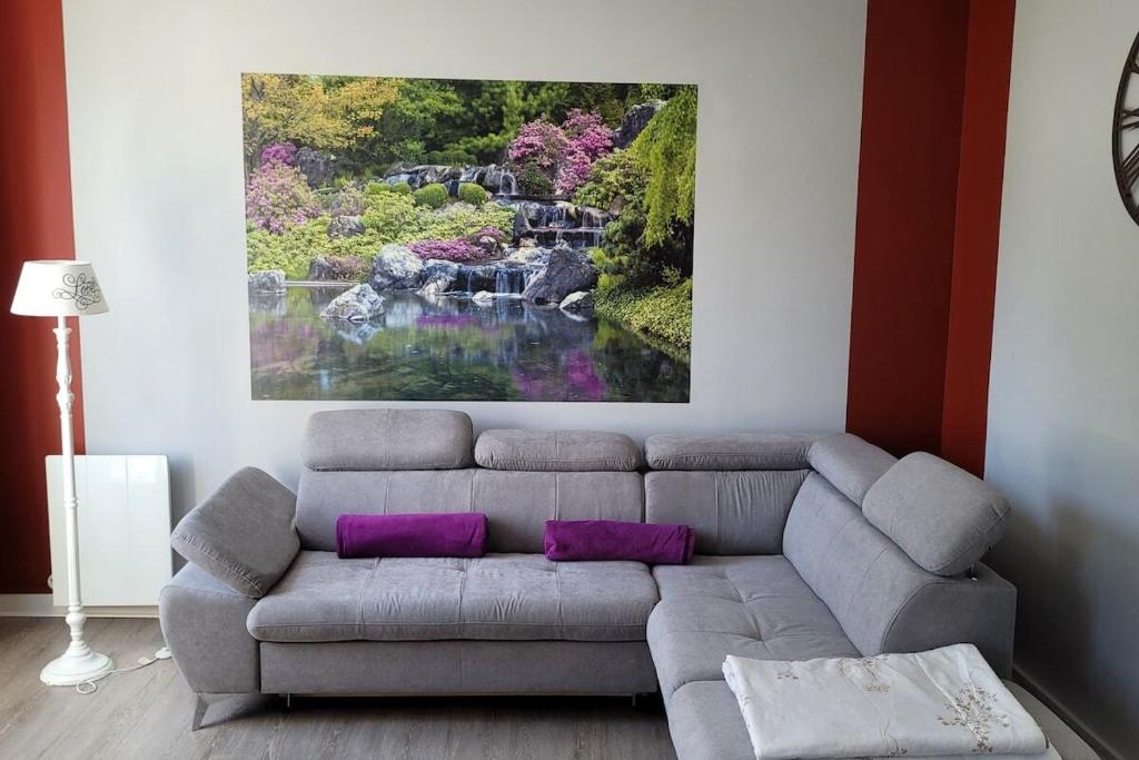 a living room with a gray couch with purple pillows at LILOA in La Bourboule
