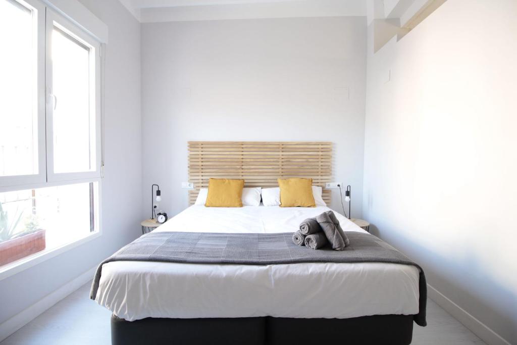 a white bedroom with a large bed with yellow pillows at Jome Stays La Nucía in La Nucía