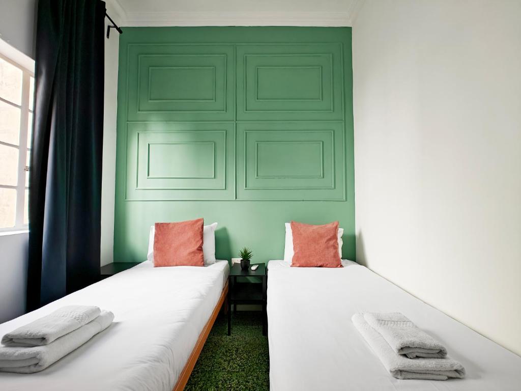two beds in a room with a green wall at Cosy room 7 in Tal-Pietà
