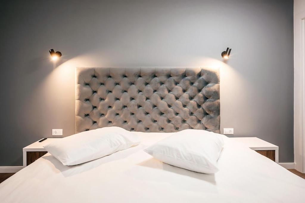 a bedroom with a large white bed with two pillows at Căsuța din Vale in Voronet