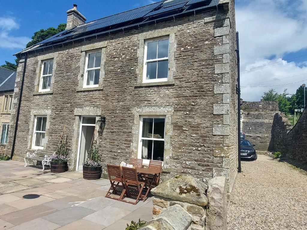 an old stone house with two chairs and a table at School House in Reeth